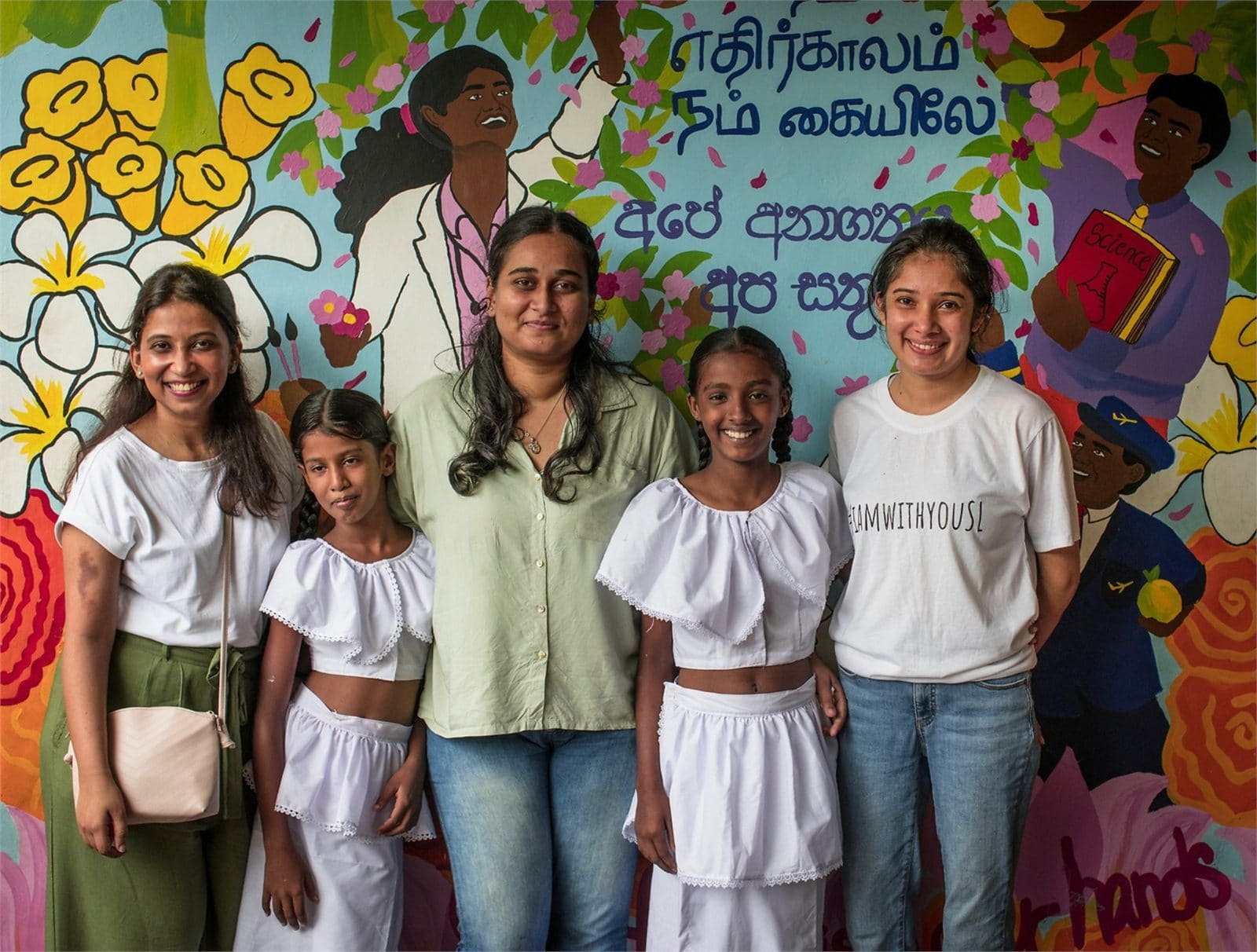 CAFS community members standing together in front of a colourful mural